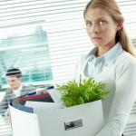 Displeased secretary standing outside the office with her personal things